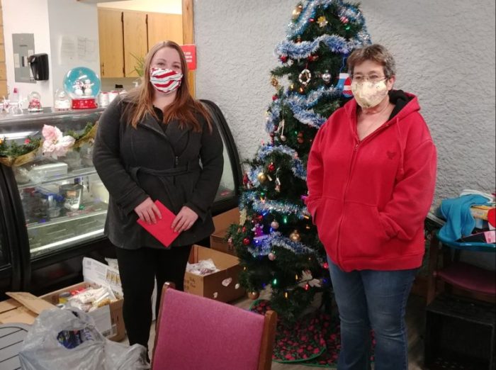 two people standing in front of a christmas tree