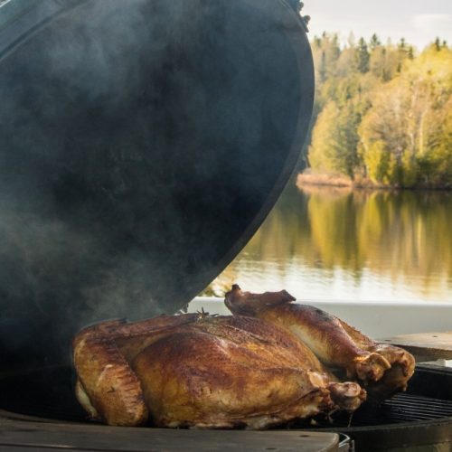 Maple & Herbs Smoked Spatchcock Turkey on the grill overlooking a lake