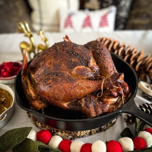 smoked whole turkey in a cast iron pan on a decorated table