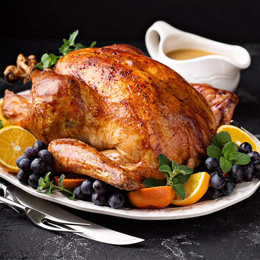 whole roasted turkey with grapes & orange slices with gravy bowl