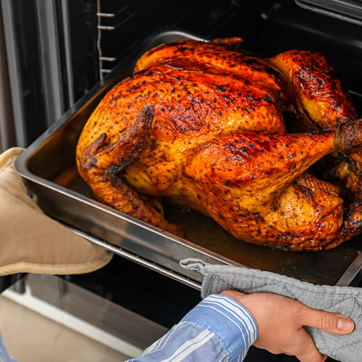a whole roasted turkey coming out of the oven