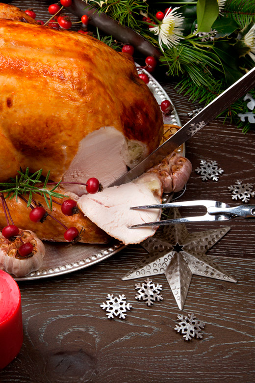 taking the first slice of a whole roasted turkey decorated for the holidays