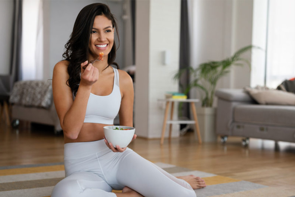 person eating food, sitting on the floor, wearing athletic clothing